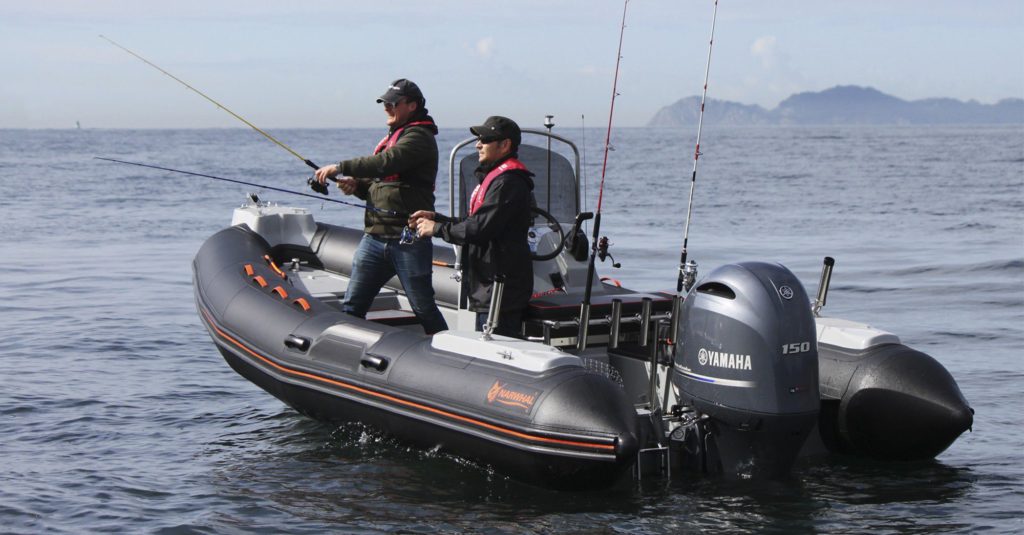 Deux personnes pêchent sur un bateau pneumatique en mer.